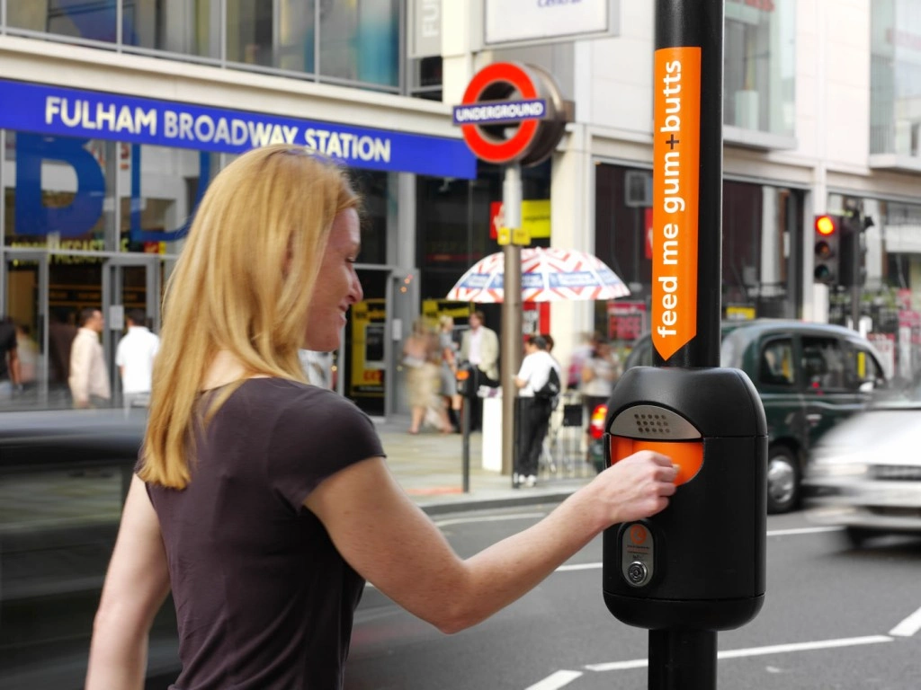 A person using a post-mounted Smartbin outside Fulham Broadway station