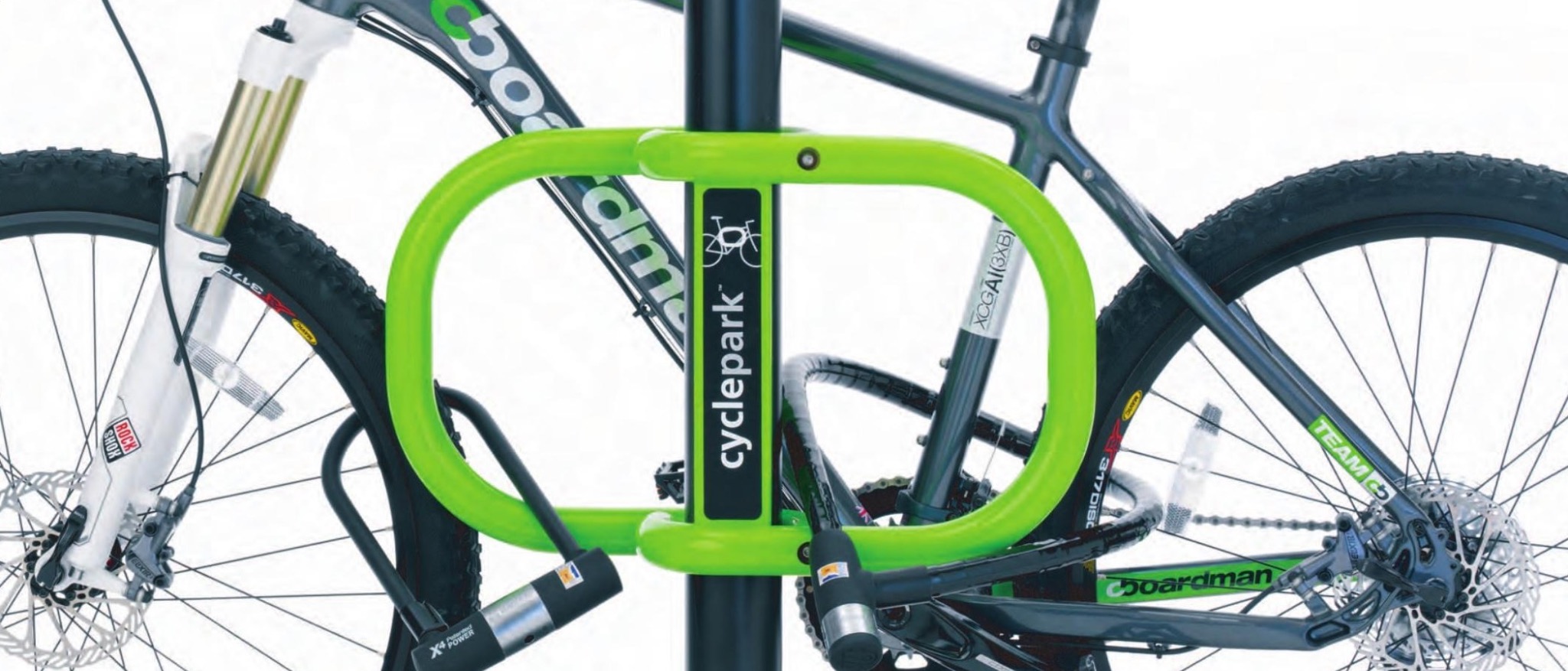 Two bicycles locked to a green Cyclepark on an existing post